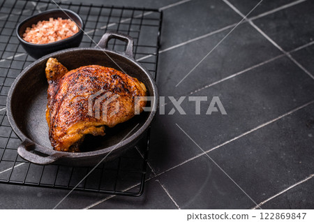 Fried roasted chicken thigh in a skillet, eco poultry meat. black background. top view 122869847