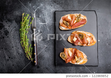 Prosciutto and pesto bruschetta, parmesan cheese and olives. black background. top view 122869852