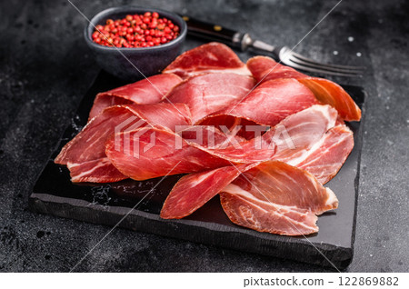 Sliced prsut prshut, Balkan cured pork meat ham. black background. top view Sliced prsut prshut, Balkan cured pork meat ham. black background. top view 122869882