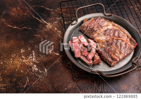 BBQ fried and sliced Chuck eye roll steak in a steel tray, prime beef meat. brown background. top view 122869885