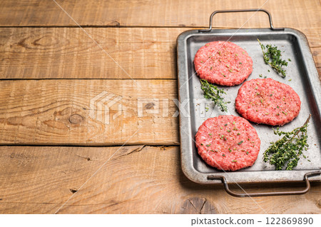 Raw hamburger minced meat patties for burgers with herbs on tray. wooden background. top view 122869890