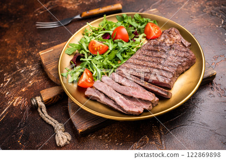 Roast dry aged Top Sirloin beef steak on plate with salad. brown background. top view 122869898