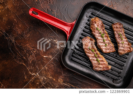 Grilled Tri tip steaks, marbled beef meat on pan with herbs. brown background. top view Grilled Tri tip steaks, marbled beef meat on pan with herbs. brown background. top view 122869901