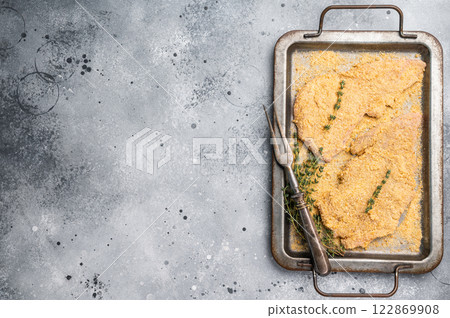 Cooking of Raw breaded Wiener Schnitzel steak in steel tray. gray background. top view Cooking of Raw breaded Wiener Schnitzel steak in steel tray. gray background. top view 122869908