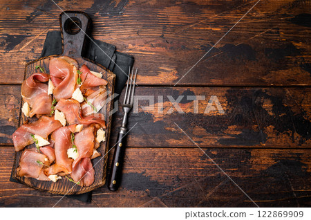 Italian Prosciutto parma ham with herbs and parmesan cheese on wooden board. wooden background. top view Italian Prosciutto parma ham with herbs and parmesan cheese on wooden board. wooden background. top view 122869909