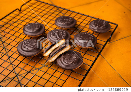 Fresh cooked Jaffa Cookies covered with chocolate and filled with jam on rack. orange background. top view 122869929
