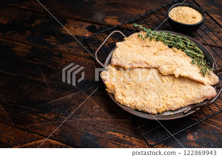 Viennese breaded raw Schnitzel steak on a tray. wooden background. top view Viennese breaded raw Schnitzel steak on a tray. wooden background. top view 122869943