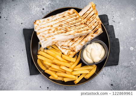 Chicken Fajita wrap sandwich with fresh salad and french fry on a plate. gray background. top view Chicken Fajita wrap sandwich with fresh salad and french fry on a plate. gray background. top view 122869961