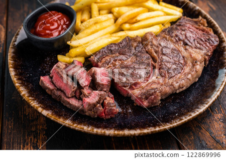 Dinner with grilled Chuck eye roll steak and french fry on a plate. wooden background. top view Dinner with grilled Chuck eye roll steak and french fry on a plate. wooden background. top view 122869996