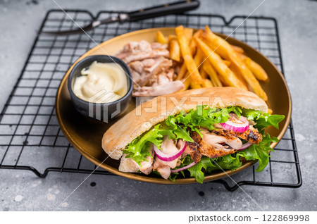 Grilled shawarma sandwich, Doner kebab with grilled meat in pita bread on a plate with french fry. grey background. top view 122869998
