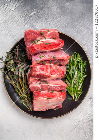 Raw Beef Kalbi Short Ribs, fresh meat with bone on plate with thyme. grey background. top view Raw Beef Kalbi Short Ribs, fresh meat with bone on plate with thyme. grey background. top view 122870017