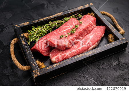 Raw skirt or machete Steak, beef meat in wooden tray with herbs. black background. top view 122870019
