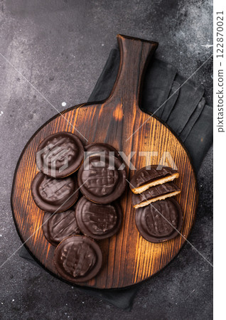 Jaffa Cookies covered with chocolate and filled with jam on wooden board. black background. top view 122870021