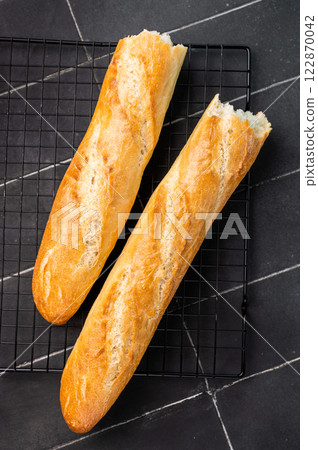 French bread baguette on a steel rack. black background. top view 122870042