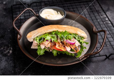 Gyros with grilled chicken meat, salad, tomato, onion, tzatziki in pita bread. black background. top view 122870109