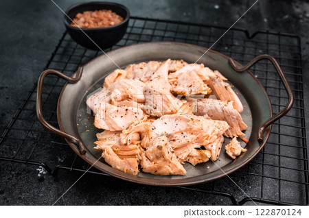 Roast salmon fillet, pulled fish meat on a steel tray. black background. Top view Roast salmon fillet, pulled fish meat on a steel tray. black background. Top view 122870124