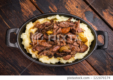 Braised Beef Cheek, Slow cooked meat with smashed potatoes in a skillet. wooden background. top view 122870174