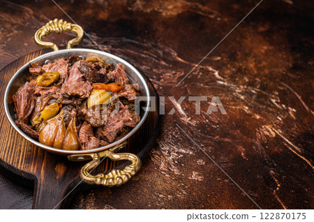 Slow cooked Beef Cheek, Braised meat with vegetables in a skillet. brown background. top view Slow cooked Beef Cheek, Braised meat with vegetables in a skillet. brown background. top view 122870175