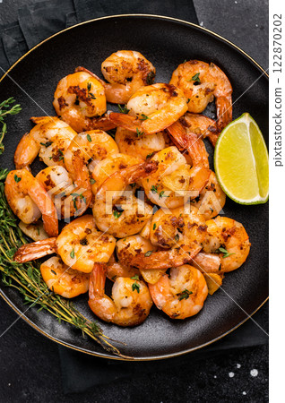 Grilled spicy Shrimps Prawns with garlic and lime in a plate. Black background. Top view Grilled spicy Shrimps Prawns with garlic and lime in a plate. Black background. Top view 122870202
