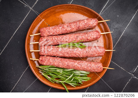 Raw Cevapcici skewers, Cevapi sausages from mince beef and pork meat. black background. top view Raw Cevapcici skewers, Cevapi sausages from mince beef and pork meat. black background. top view 122870206