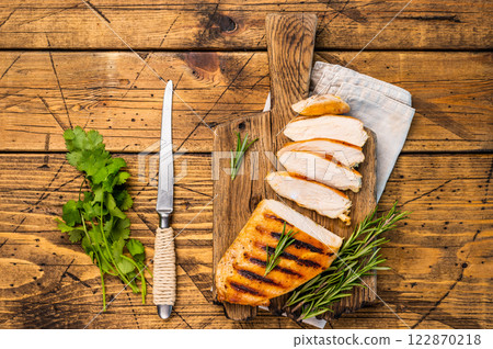 Grilled and sliced Chicken breasts on cutting board, grilled poultry meat, top view, wooden background. Grilled and sliced Chicken breasts on cutting board, grilled poultry meat, top view, wooden background. 122870218