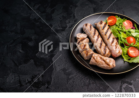 Salad with grilled beef and pork sausages on plate. black background. top view Salad with grilled beef and pork sausages on plate. black background. top view 122870333