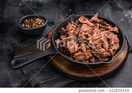 Traditional barbecue pulled beef, Slow cooked meat cooked in a smoker. black background. top view Traditional barbecue pulled beef, Slow cooked meat cooked in a smoker. black background. top view 122870359