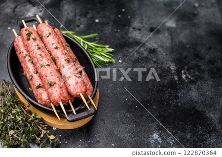 Raw shish kebab, arabic kofta kofte kebab from mince lamb and beef meat on Skewer. black background. top view 122870364