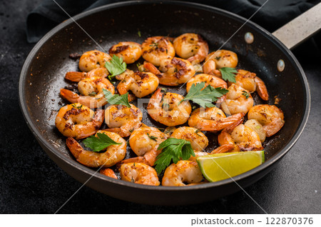 Fried Shrimps Prawns with garlic and butter in a skillet. Black background. Top view 122870376