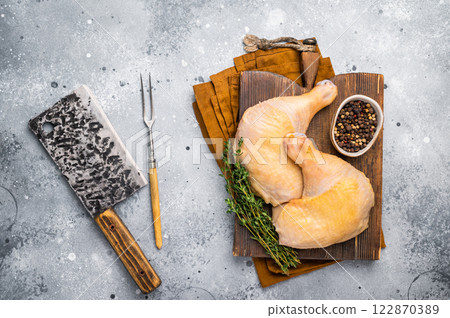 Raw chicken legs on wooden cutting board, eco poultry meat on gray background, top view Raw chicken legs on wooden cutting board, eco poultry meat on gray background, top view 122870389