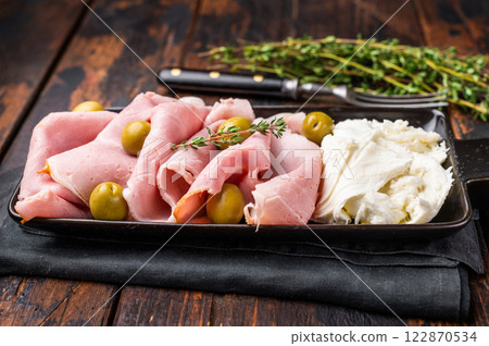Italian antipasto with Sliced Prosciutto Cotto ham, green olives and mozzarella. wooden background. top view 122870534