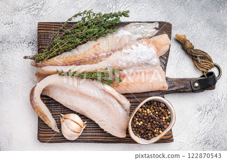 fresh Raw Pollock fish fillets on a wooden board with herbs. white background. top view 122870543