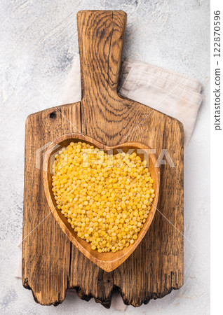 Dry Ptitim pasta, Israeli couscous in wooden bowl. white background. top view Dry Ptitim pasta, Israeli couscous in wooden bowl. white background. top view 122870596