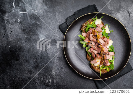 Toast with duck breast meat, foie gra, arugula and cheese on plate. black background. top view Toast with duck breast meat, foie gra, arugula and cheese on plate. black background. top view 122870601