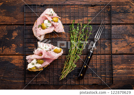Italian sandwich Bruschetta with Prosciutto Cotto ham, burrata mozzarella and olives. wooden background. top view 122870629