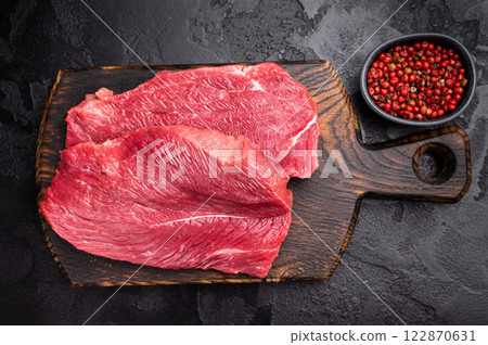 Raw Boar meat steak, uncooked Game Meat on cutting board. black background. top view 122870631