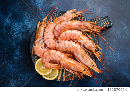 Ready for cooking Red Argentine shrimps, raw Prawns Langostino Austral on wooden board. blue background. top view 122870634