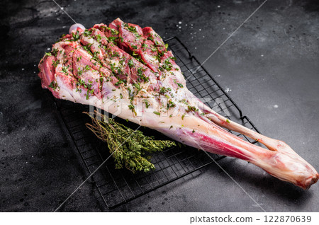 Whole raw Goat leg Marinated with herbs and olive oil. black background. top view 122870639