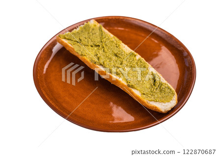 Delicious green pesto spread on toasted bread, garnished with herbs isolated on white background 122870687