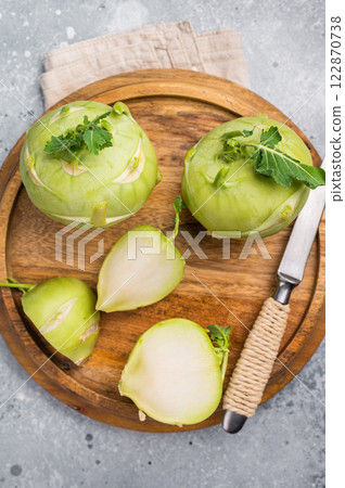 Raw kohlrabi sliced on pieces on wooden tray. grey backround. top view 122870738