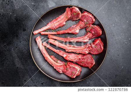 Fresh mutton chops, raw lamb meat cutlets on a plate. black background. top view Fresh mutton chops, raw lamb meat cutlets on a plate. black background. top view 122870786