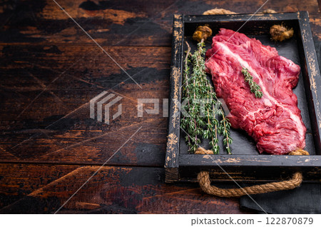 Uncooked hanging tender beef steak, Hanger steak in wooden tray with herbs. wooden background. top view Uncooked hanging tender beef steak, Hanger steak in wooden tray with herbs. wooden background. top view 122870879