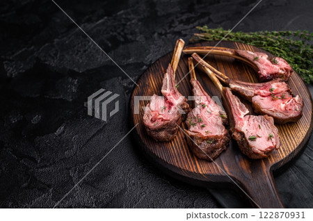 French roast lamb chops, mutton meat steaks on wooden board. black background. top view French roast lamb chops, mutton meat steaks on wooden board. black background. top view 122870931