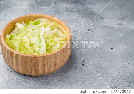 Fresh raw iceberg lettuce salad cut leaves in wooden bowl. grey background. top view Fresh raw iceberg lettuce salad cut leaves in wooden bowl. grey background. top view 122870947