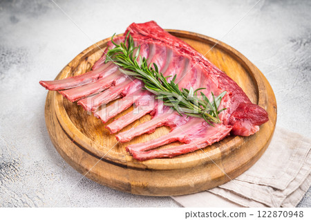 Uncooked rack of lamb, raw mutton chops on wooden board. grey background. top view 122870948