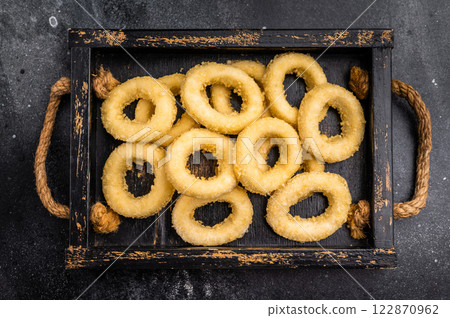 Raw squid rings with breading, uncooked calamari snack. black background. top view 122870962