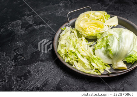 Fresh raw iceberg lettuce salad cut leaves. black background. top view Fresh raw iceberg lettuce salad cut leaves. black background. top view 122870965