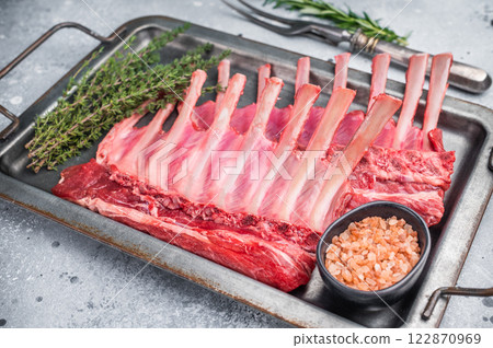 Raw mutton meat for chops steaks, uncooked rack of lamb on steel tray with herbs. grey background. top view 122870969