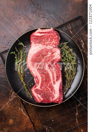 Chuck eye roll steak, raw marbled beef meat with herb for cooking. brown background. top view 122871004