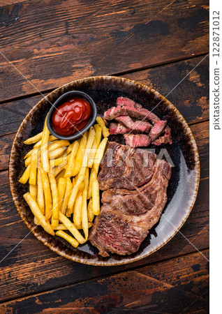 Dinner with grilled Chuck eye roll steak and french fry on a plate. wooden background. top view 122871012